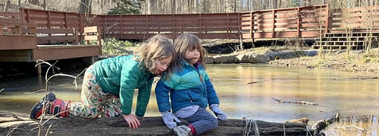 Nature Preschool - two children playing on a log