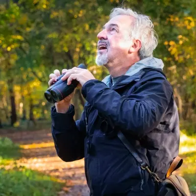 man holding binoculars in a wooded area