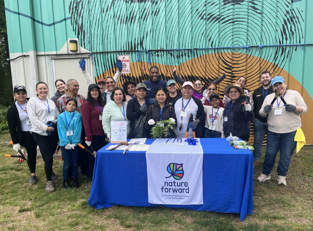 Group of people standing behind a blue table with nature forward logo